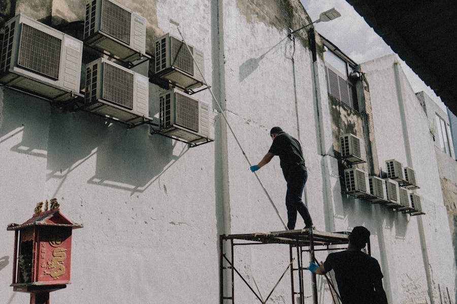 Technicians servicing multiple outdoor air conditioning units mounted on a building