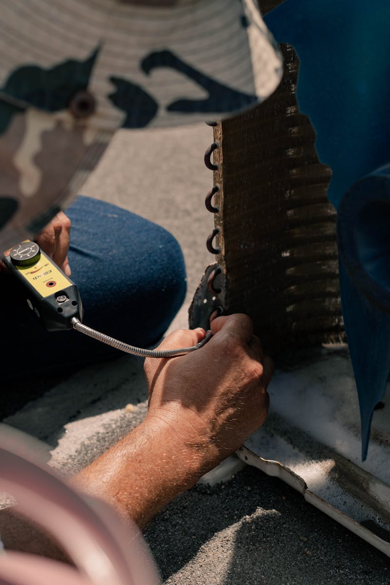 Technician inspecting an outdoor air conditioning unit coil