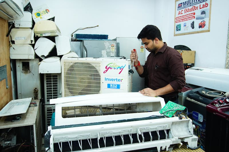 Air conditioner technician repairing components in a workshop